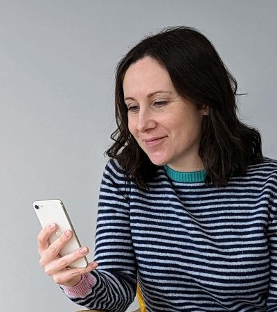 Dr Katy Hill looking at her phone and smiling